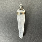 Clear white selenite crystal pendant with a tapered hexagonal shape set in a polished sterling silver top clasp against a dark textured background.
