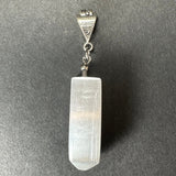 Translucent white selenite crystal pendant with a pointed bottom, attached to a sterling silver clasp engraved with hallmarks, on a gray background.