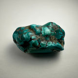 Close-up image of a turquoise nugget showing its vibrant blue-green surface and natural mineral texture