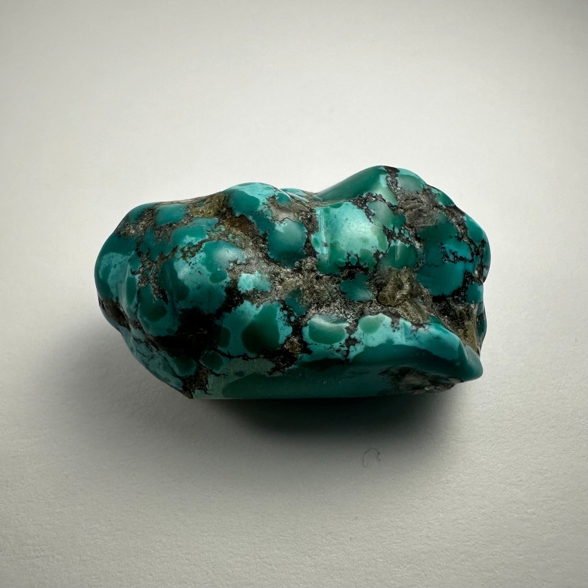 Close-up image of a turquoise nugget showing its vibrant blue-green surface and natural mineral texture