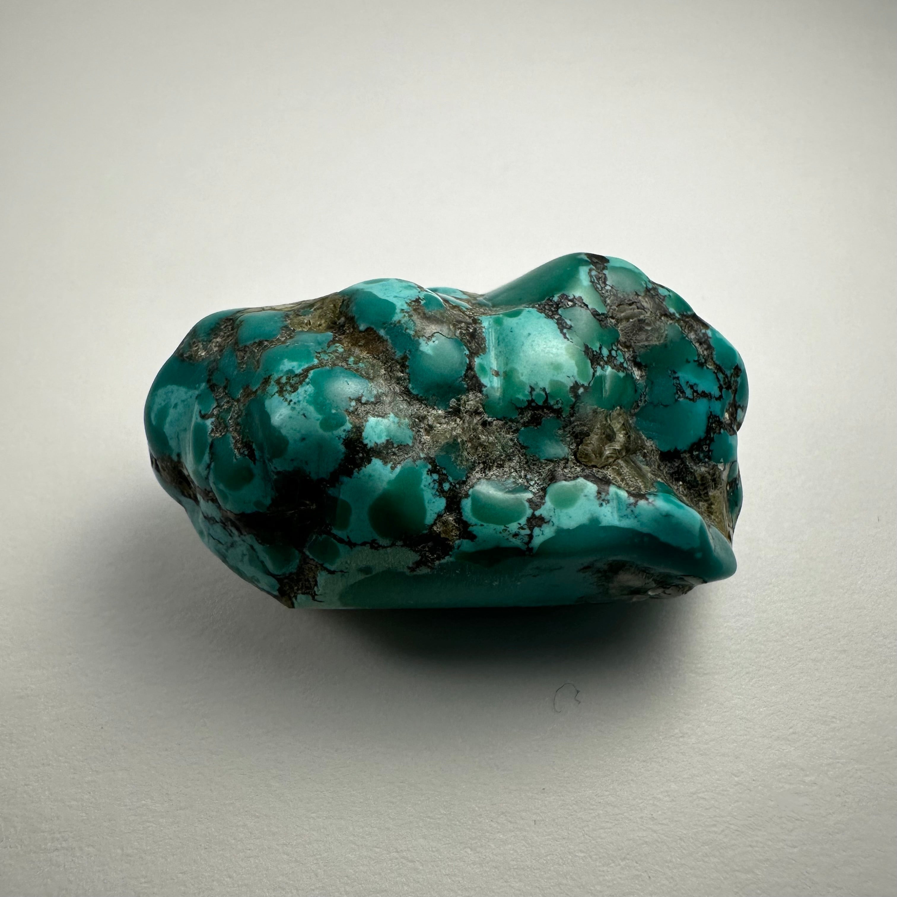 Close-up image of a turquoise nugget showing its vibrant blue-green surface and natural mineral texture