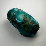 Turquoise nugget with vibrant blue-green color and dark brown to black matrix patterns, shown against a light gray background in a close-up view.