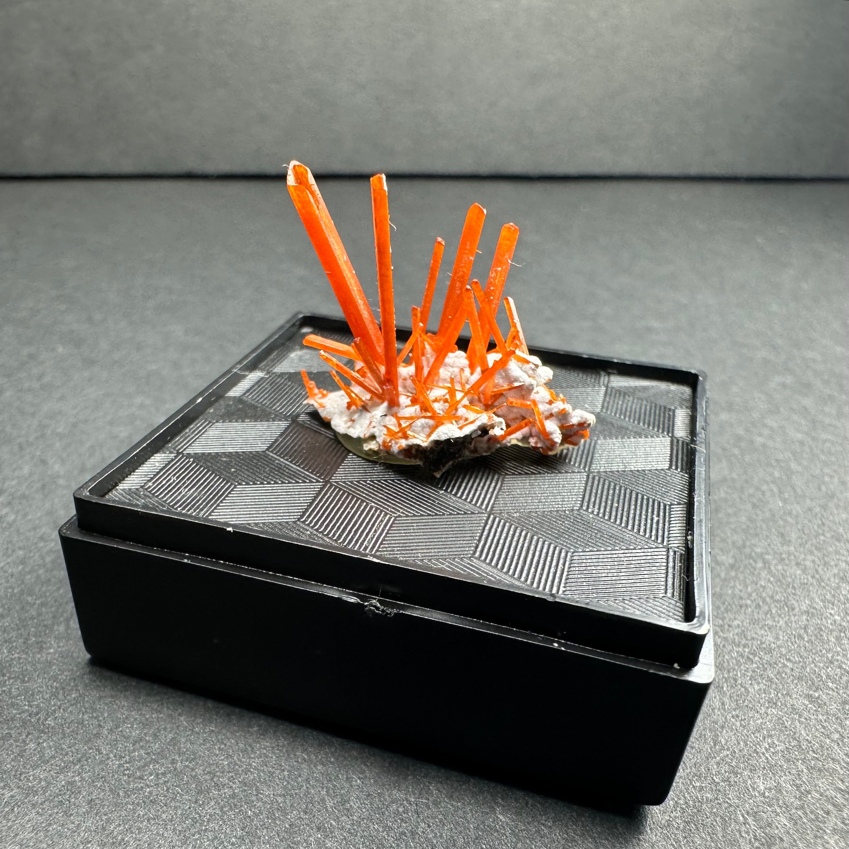 Crocoite mineral specimen on matrix displayed in a clear acrylic box