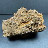Rough wulfenite cluster with earthy brown and orange matrix, featuring small, shiny crystal faces from Maoniuping Mine, Sichuan, China, shown on dark background.