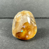 Polished fire agate with amber and honey brown tones, iridescent flashes, and a smooth glossy surface against a dark gray background.
