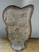 Ammonite fossil embedded in a beige and brown matrix stone sculpture with a rounded top and irregular shape, displayed upright against a gray background.