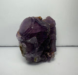 Cluster of purple cubic fluorite crystals with translucent and slightly reflective faces on a white background