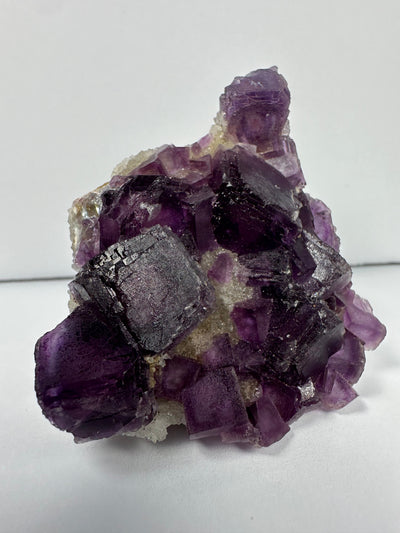 Purple cubic fluorite crystals resting on matrix from China, measuring 2 x 1 x 2.5 inches