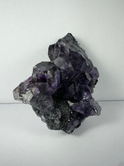 Purple dodecahedral fluorite crystals with white calcite on matrix, displayed from multiple angles