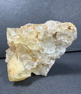 Cluster of yellow and clear fluorite crystals with cubic shapes and a slightly translucent appearance, resting against a dark gray background.