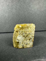 Yellowish, translucent diamond quartz crystals embedded in a rough, textured siderite matrix, displayed against a soft gray background.