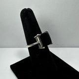 Silver ring with a square black onyx stone set in four prongs, displayed upright on a black velvet ring holder against a plain white background.