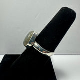 Silver ring with a polished labradorite stone set in a bezel, displayed on a black ring holder against a plain white background.