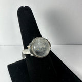 Silver ring with a round translucent moonstone cabochon set in a smooth bezel, displayed on a black velvet ring stand against a white background