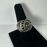 Silver ring with a round labradorite stone center and intricate lattice and swirling designs displayed on a black velvet stand.