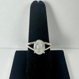 Silver ring with an oval moonstone cabochon set in a simple split shank design, displayed on a black velvet stand against a light background.