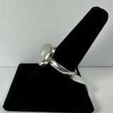 Silver ring with a domed moonstone set in a bezel mount displayed on a black velvet ring holder against a white background.
