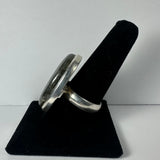 Silver ring with an oval labradorite stone set in a simple bezel, displayed on a black velvet finger stand against a plain white background.