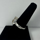 Silver ring with a large, rough, translucent quartz crystal set on top, displayed on a black velvet ring holder against a plain white background.