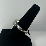 Silver ring with a large round moonstone set in a simple bezel on a black ring display against a plain light background.
