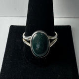 Silver ring with a polished dark green serpentine oval stone set in a split shank band, displayed on a black velvet ring holder.