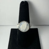 Silver ring featuring a round moonstone with a cloudy, translucent appearance set on a black velvet ring display.