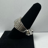 Silver ring with an engraved geometric pattern on the band, featuring a round moonstone cabochon, displayed on a black velvet cone stand.