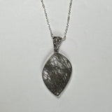 Marquise-shaped rutilated quartz pendant with black needle-like inclusions set in a silver bezel, hanging from a twisted silver chain on a neutral background.