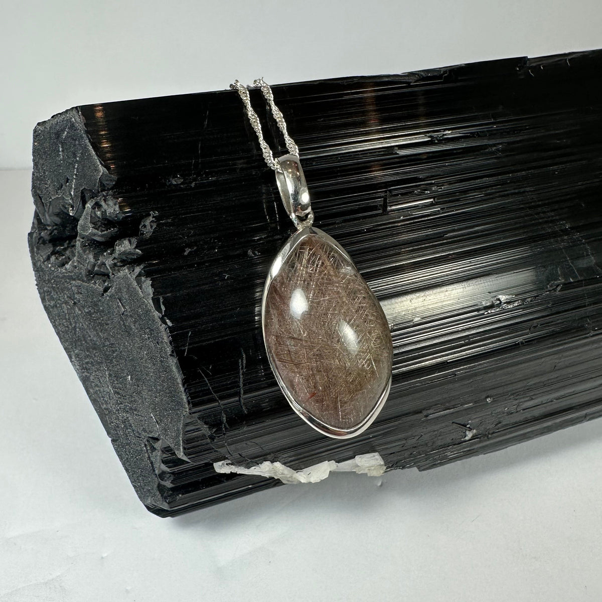 Silver Rutile Teardrop Pendant showing freeform quartz cabochon with needle-like inclusions set in sterling silver clasp