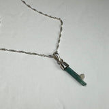Silver chain necklace with a pendant featuring a slender, green tourmaline crystal with a small, rough white crystal attached.
