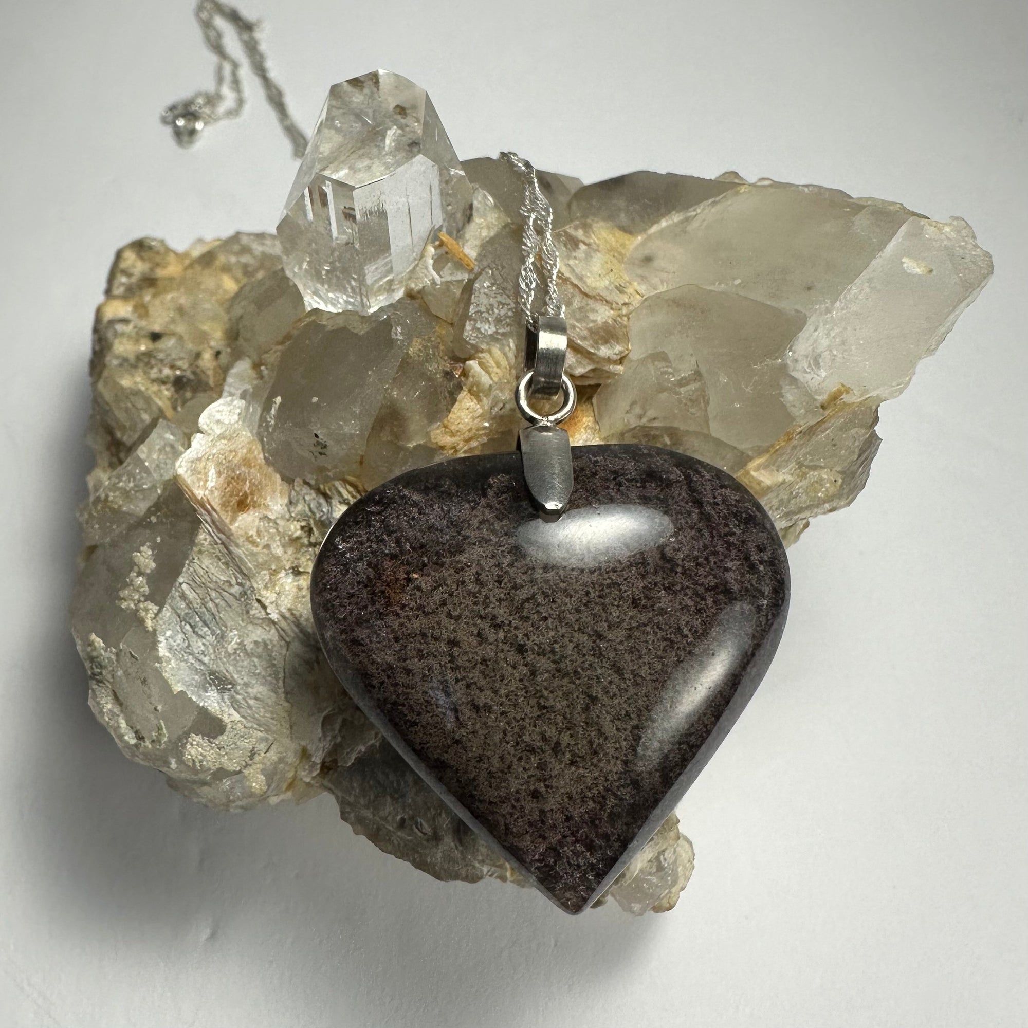 Clear heart-shaped quartz pendant with dark lodalite inclusions set in silver