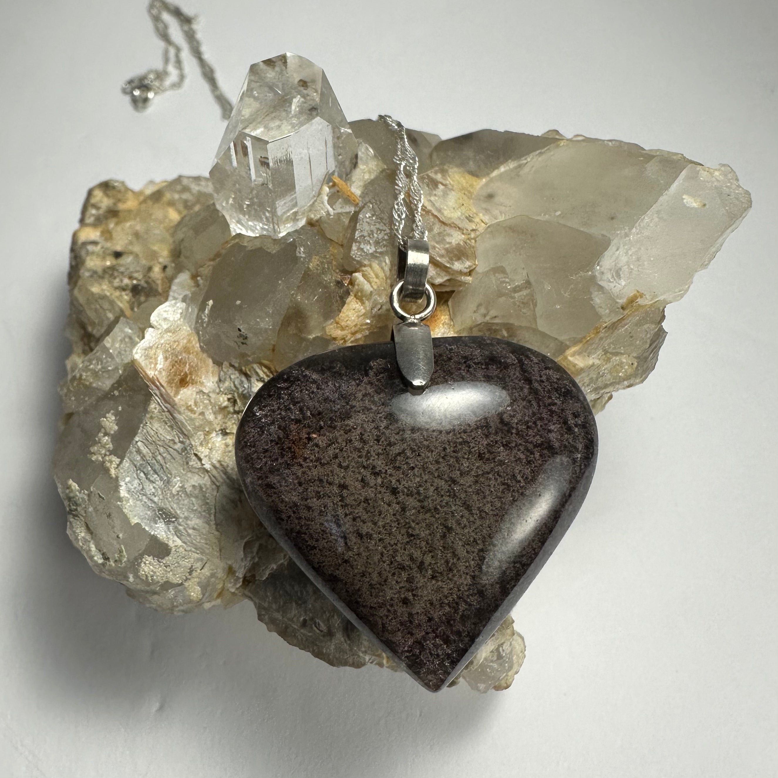 Clear heart-shaped quartz pendant with dark lodalite inclusions set in silver