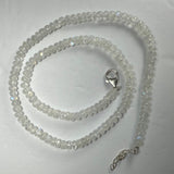 Coiled moonstone rondelle bead necklace with translucent white beads showing subtle blue flashes, finished with a silver lobster clasp and extender chain on a white background.