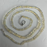 Graduated translucent opal beads in pale yellow and clear tones strung in a necklace with a silver lobster clasp and chain extender on a white background.