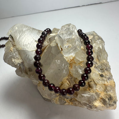 Close-up photo of a Red Garnet round bead necklace featuring glossy deep red beads and a fine silver chain clasp.