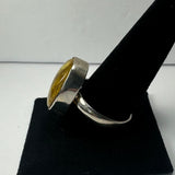Silver ring with a thick rounded band and a large domed amber stone set in a wide bezel, displayed on a black velvet ring cone.