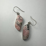 Pair of hooked earrings with irregular rhodonite stones featuring pink, black, and gray marbled patterns set in silver-tone frames.