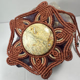 Handwoven flower-shaped brown macrame necklace featuring a large round beige jasper cabochon with natural patterns at center.