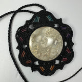 Round jasper cabochon with natural beige and brown patterns at center of black hand-woven flower necklace featuring subtle teal, purple, and orange thread accents.
