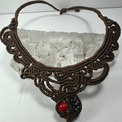 Handmade macrame choker with coral bead on black fabric background