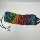 Handwoven bracelet displaying a gradient of rainbow colors segmented by black lines with two black braided cords ending in white beads.