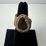 Handmade woven beige cord ring featuring a polished teardrop-shaped dark stone, displayed on a black velvet ring holder.
