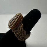 Close-up of a handmade woven ring featuring brown and beige cords with a small stone set in the center, displayed on a black velvet ring holder.