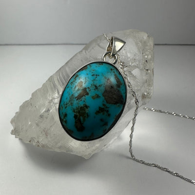 Turquoise Pendant with oval turquoise stone in silver setting on white background