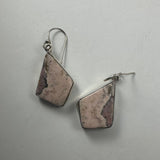Pair of geometric rhodonite stone earrings with pink and black marbled patterns set in silver hooks on a light background.