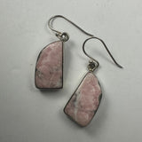 Pair of drop earrings featuring geometric rhodonite stones with pink and black marbled patterns set in silver-tone metal hooks against a plain light background.