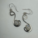 Pair of silver earrings with a freeform looping design, each featuring a smooth, oval moonstone set near the curve's base on a light gray background.