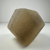 Light brown translucent fluorite dodecahedron crystal with a rough surface texture, shown upright on a white background.