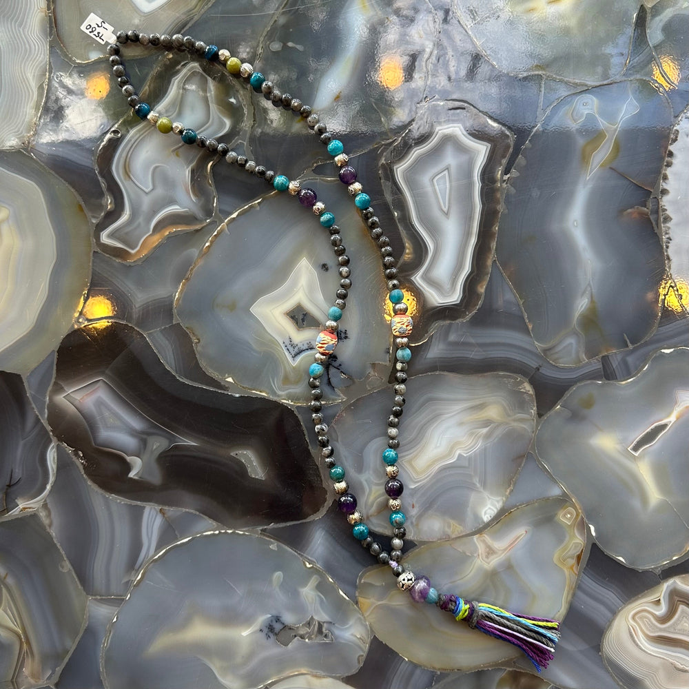 Close-up view of Larvikite Mala with mixed stone beads on a neutral surface