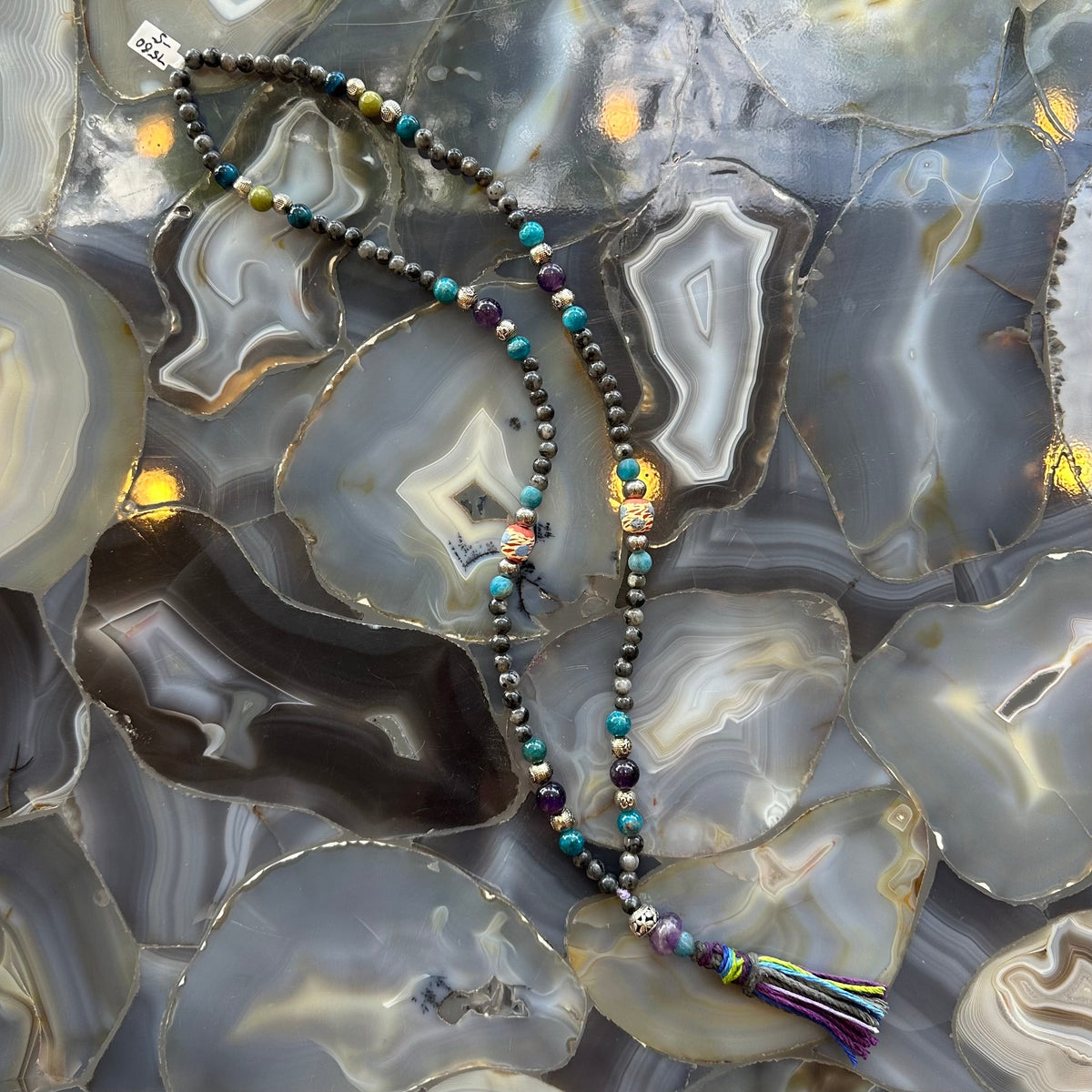 Close-up view of Larvikite Mala with mixed stone beads on a neutral surface